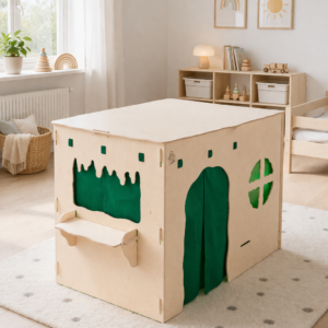 Quadratischer Spielkubus aus hellem Holz mit grün hervorgehobener Rundtür und Fenstern in hellem Kinderzimmer.